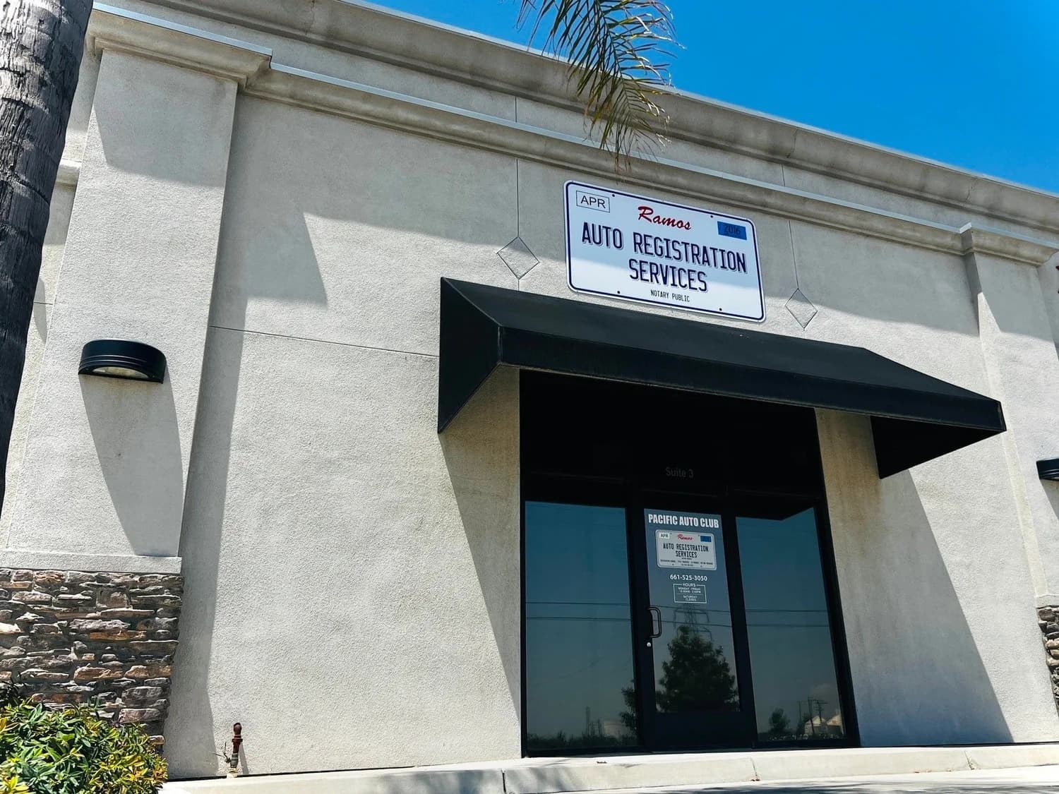 The Ramos Auto Registration Services office on E Norris Rd in Bakersfield: white building, black awning, license-plate sign over the door